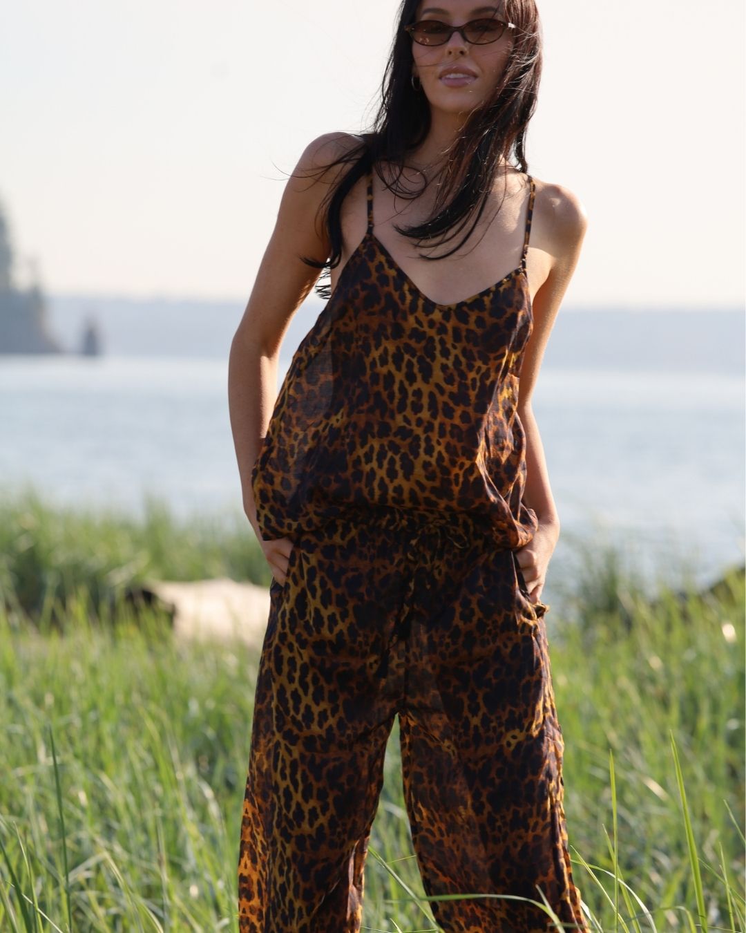 Woman wearing a leopard print jumpsuit standing in grass with a blurred background