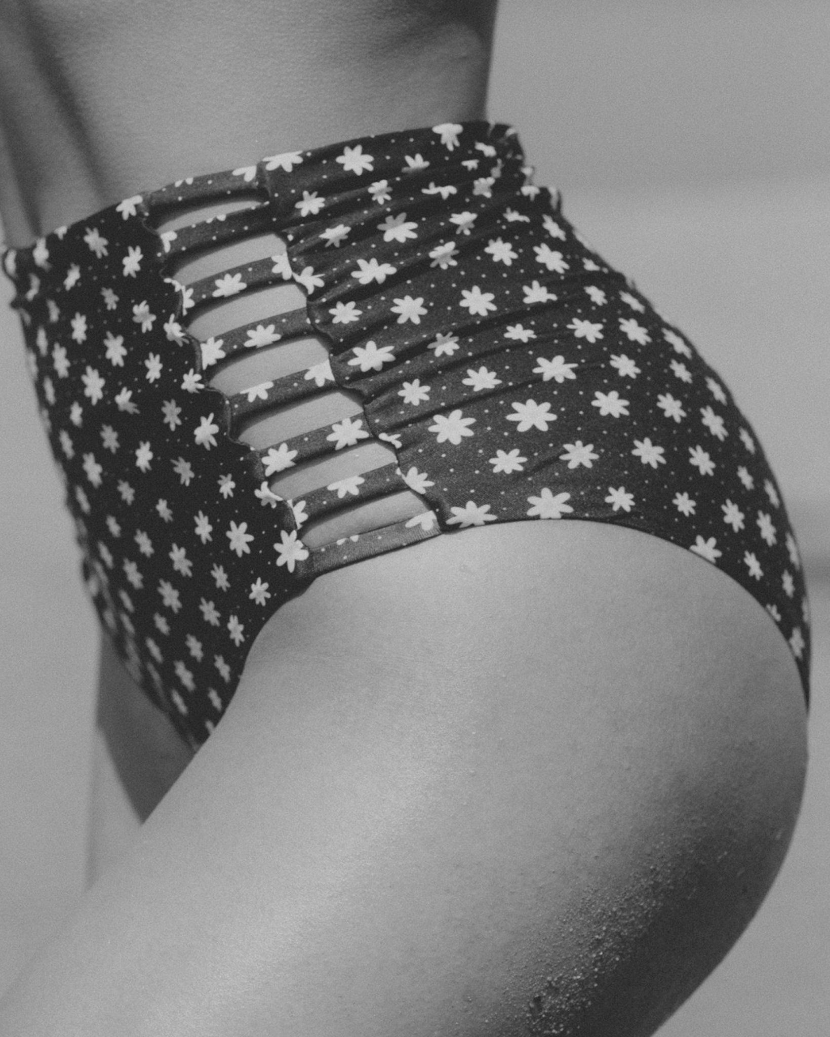 A model wearing a high-waisted swimsuit with cut-out details on the sides.