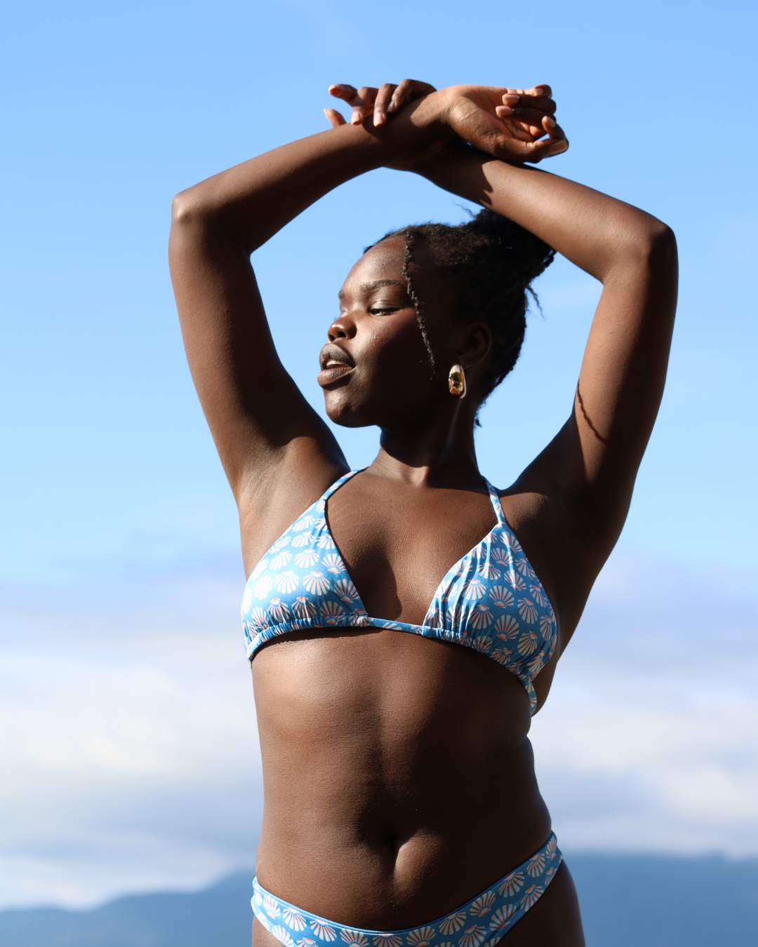 Woman in a blue bikini against a clear sky. Womens Sustainable swimwear. Designed in Canada.