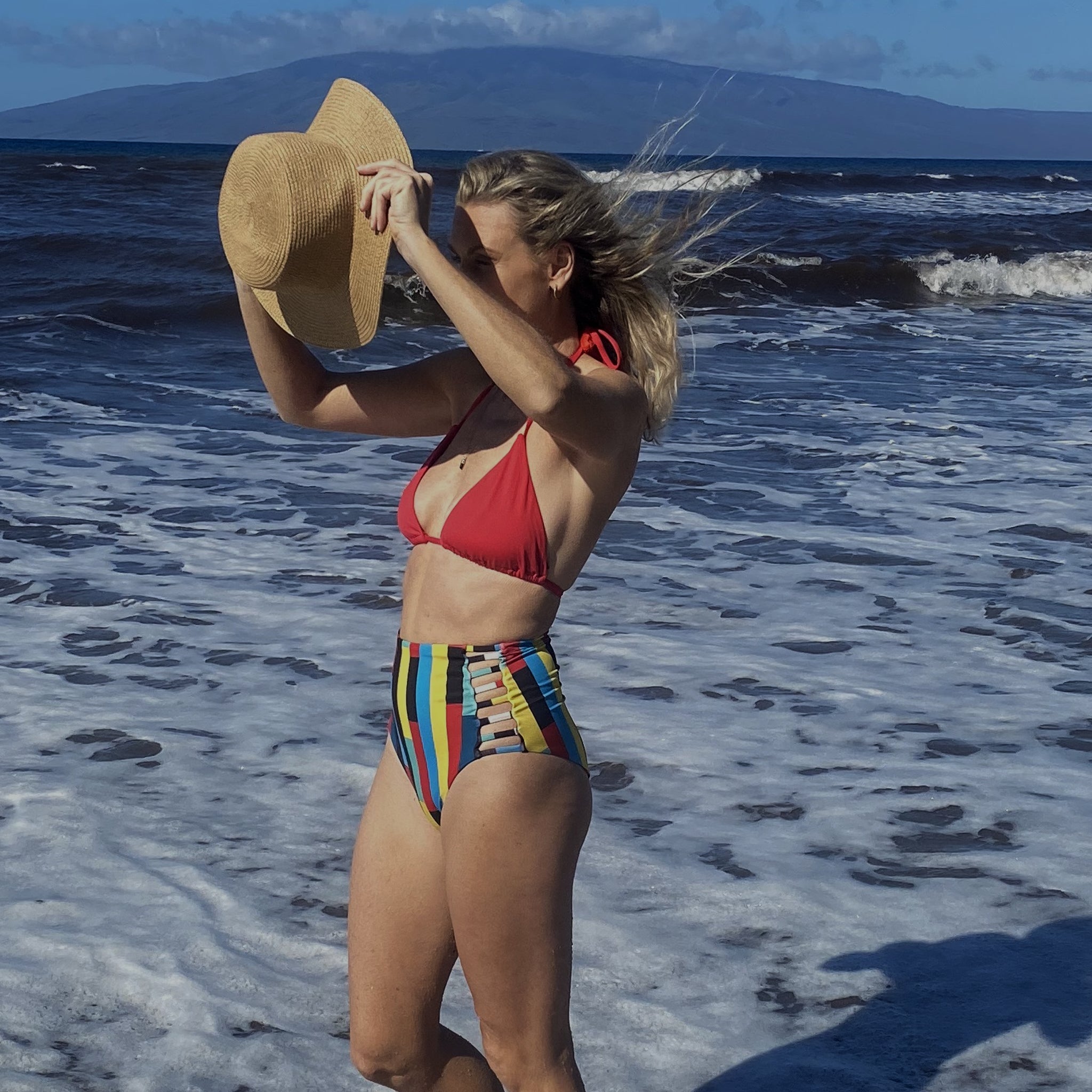 A model wearing a high-waisted black swimsuit with cut-out details on the sides.